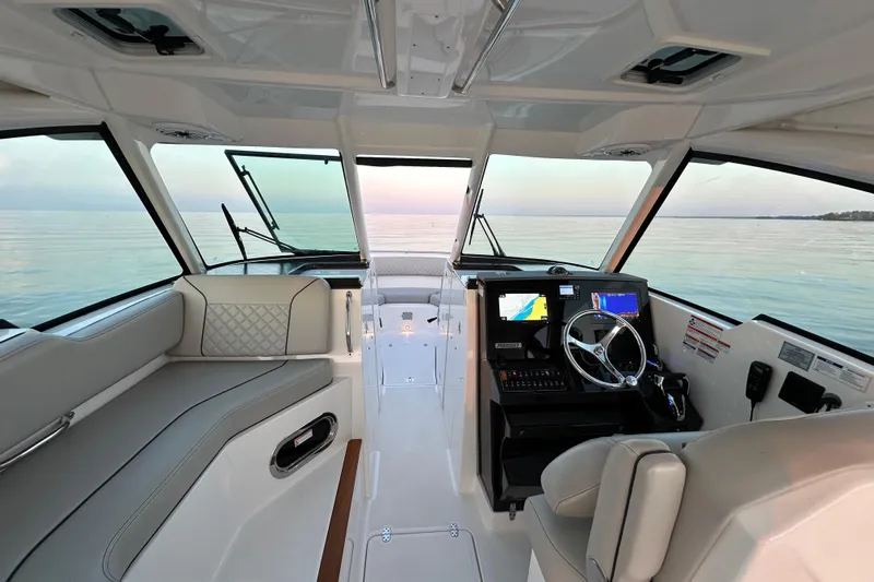  Yacht Photos Pics 2023 Pursuit DC 326 Dual Console interior with modern helm and seating, overlooking serene waters.