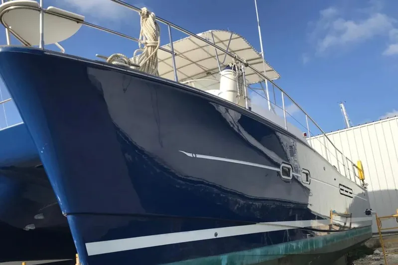 Mangata Yacht Photos Pics 2003 Lagoon Power 43 yacht with sleek blue hull, docked under clear sky.
