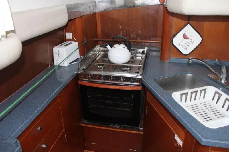 Mangata Yacht Photos Pics Compact kitchen in 2003 Lagoon Power 43 yacht with stove, sink, and toaster.