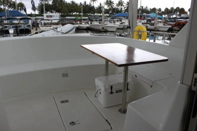 Mangata Yacht Photos Pics 2003 Lagoon Power 43 yacht deck with table and cooler, docked at marina.