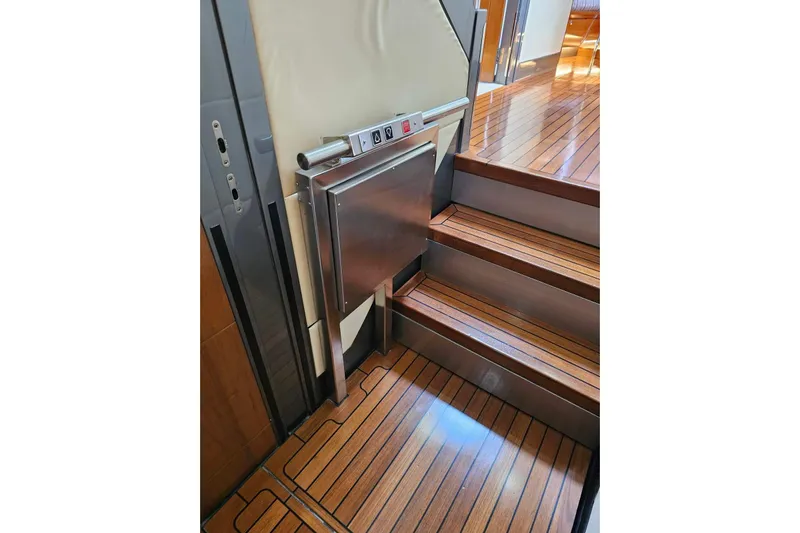 Gramac V Yacht Photos Pics Staircase with a compact lift on a 2007 Azzura 76 yacht, featuring wooden flooring.