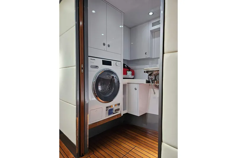 Gramac V Yacht Photos Pics Laundry area on 2007 Azzura 76 yacht with washer, cabinets, and wood flooring.