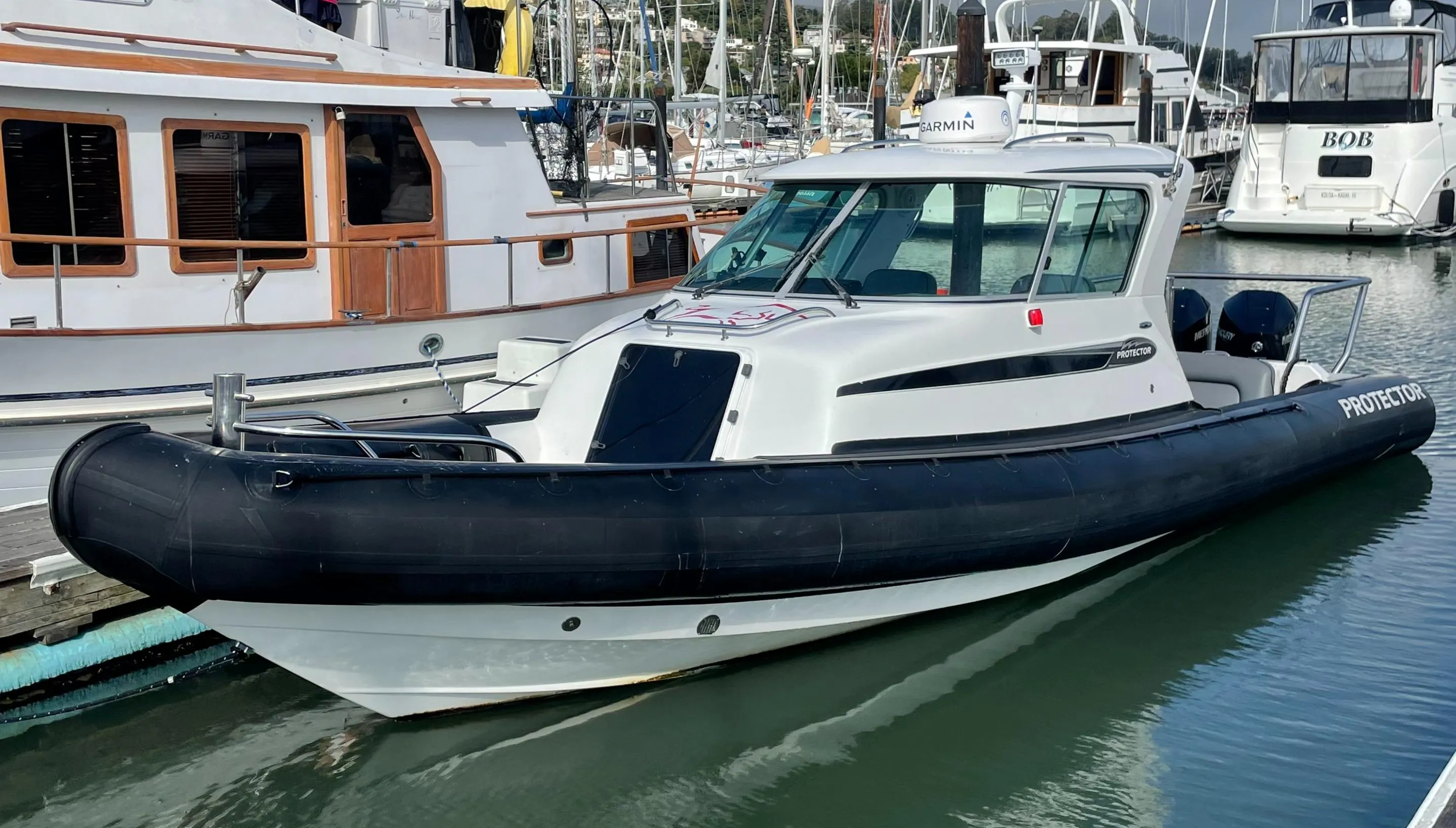 2018 Protector Targa 30 boat docked in marina, featuring sleek design and black rubber fender.