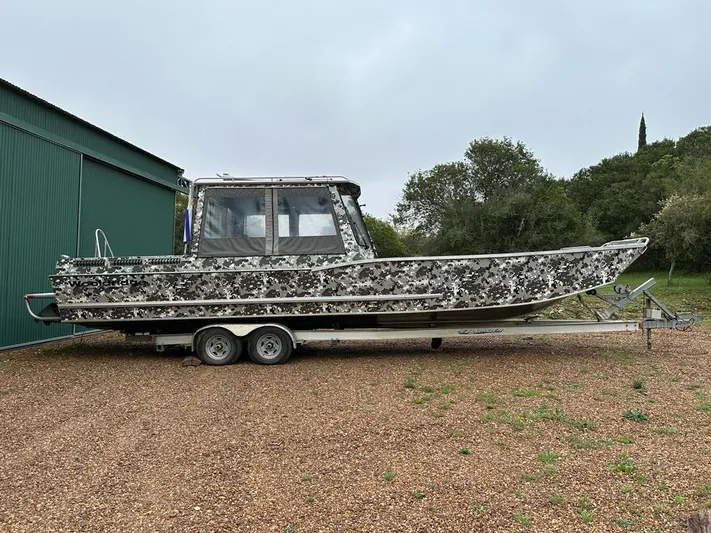 Commander Yacht Photos Pics 2014 Wooldridge 31 boat with camouflage design on a trailer near a green building.