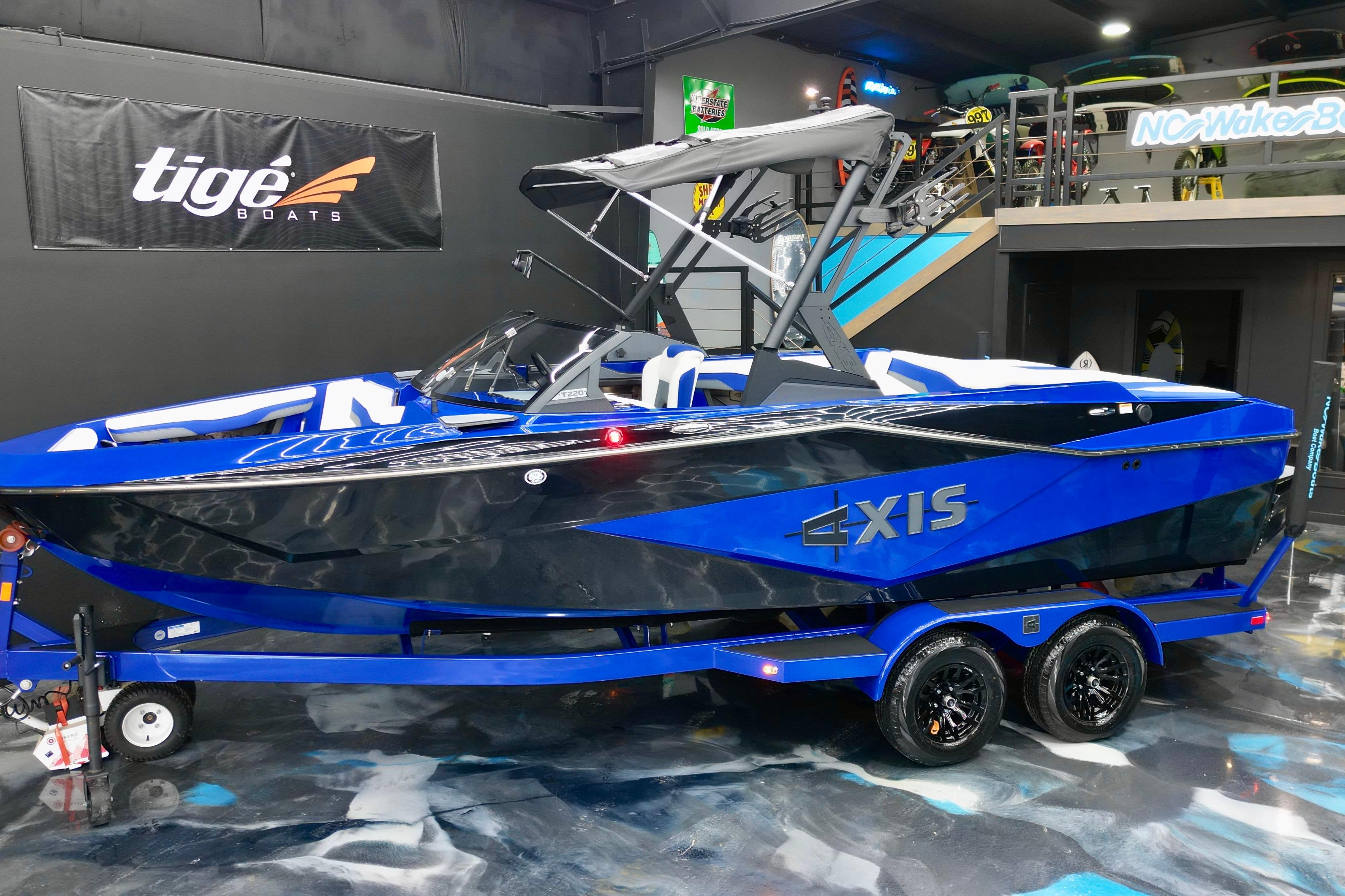 2025 Axis T220 boat in showroom, blue and black design, on trailer.