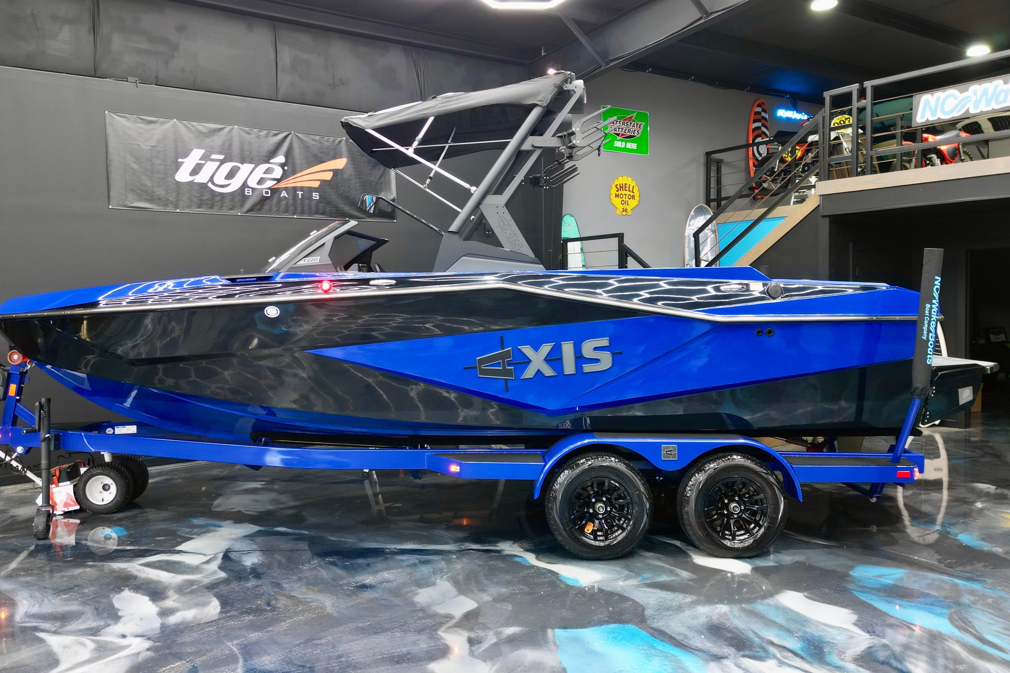 2025 Axis T220 boat in showroom, vibrant blue and black design on trailer.