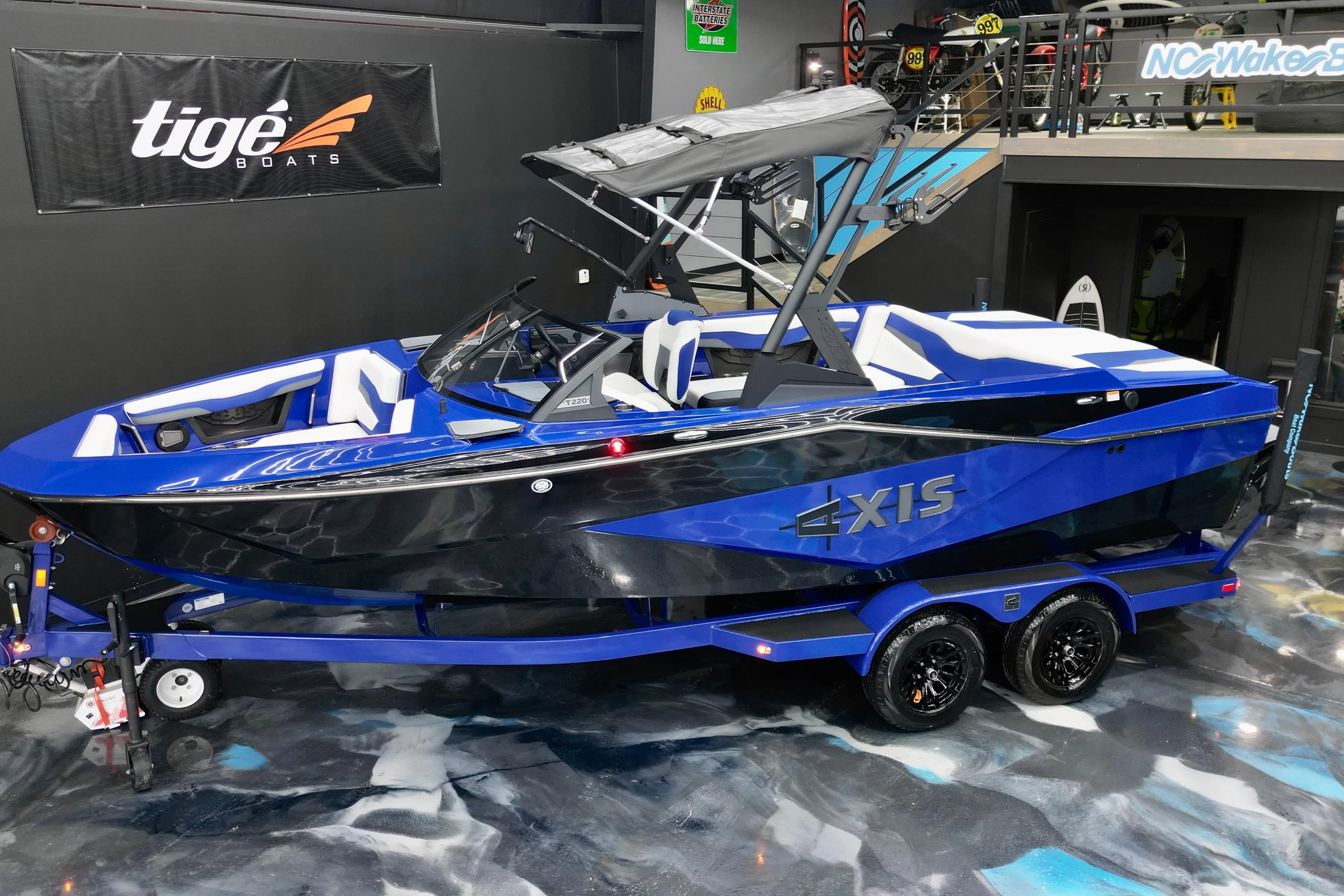 2025 Axis T220 boat in showroom, blue and black design, on trailer.