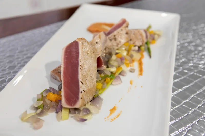  Yacht Photos Pics Seared tuna slices on a bed of diced vegetables, elegantly plated.