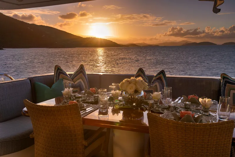  Yacht Photos Pics Luxurious dining setup on 1994 Broward Marine Raised Pilothouse yacht at sunset.