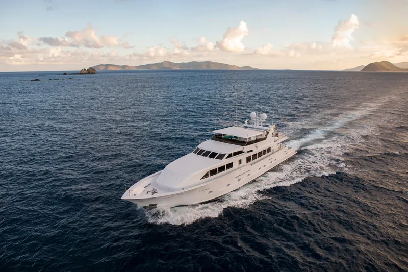  Yacht Photos Pics Luxurious 1994 Broward Marine Raised Pilothouse yacht cruising in open ocean at sunset.