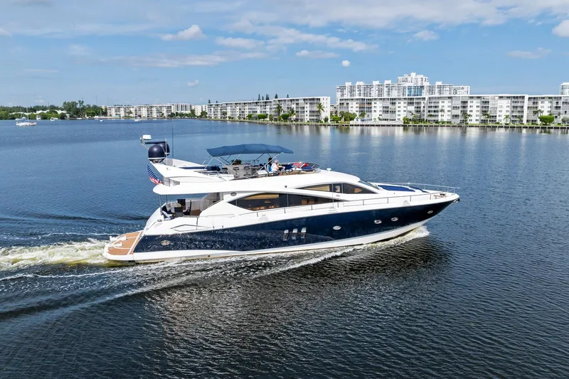 Persistence Yacht Photos Pics 2006 Sunseeker 75 Yacht cruising on a calm waterway with modern buildings in the background.