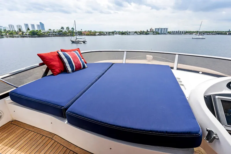 Persistence Yacht Photos Pics Sunseeker 75 Yacht 2006 with blue sunbed and red pillows on deck, overlooking calm waters.