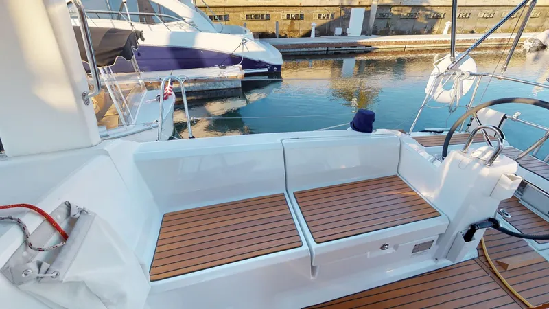 Wanderlust Yacht Photos Pics 2019 Beneteau Oceanis 38.1 yacht cockpit with wooden seating, docked by the water.