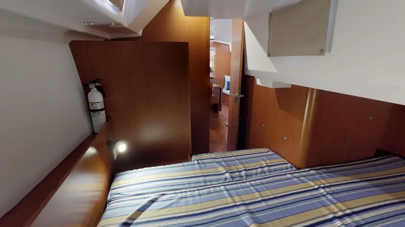 Wanderlust Yacht Photos Pics Cozy cabin interior of 2019 Beneteau Oceanis 38.1 with striped bedding and wooden finish.