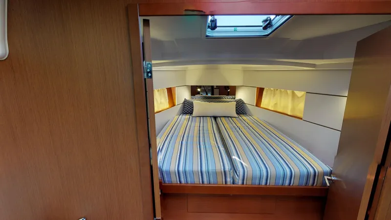 Wanderlust Yacht Photos Pics Cozy cabin interior of 2019 Beneteau Oceanis 38.1 with striped bedding and skylight.