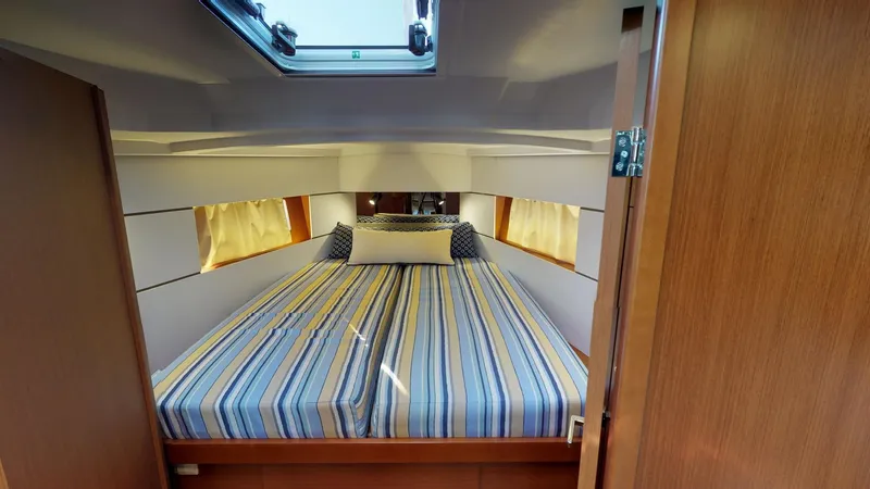 Wanderlust Yacht Photos Pics Cozy cabin interior of 2019 Beneteau Oceanis 38.1 with striped bedding and natural light.