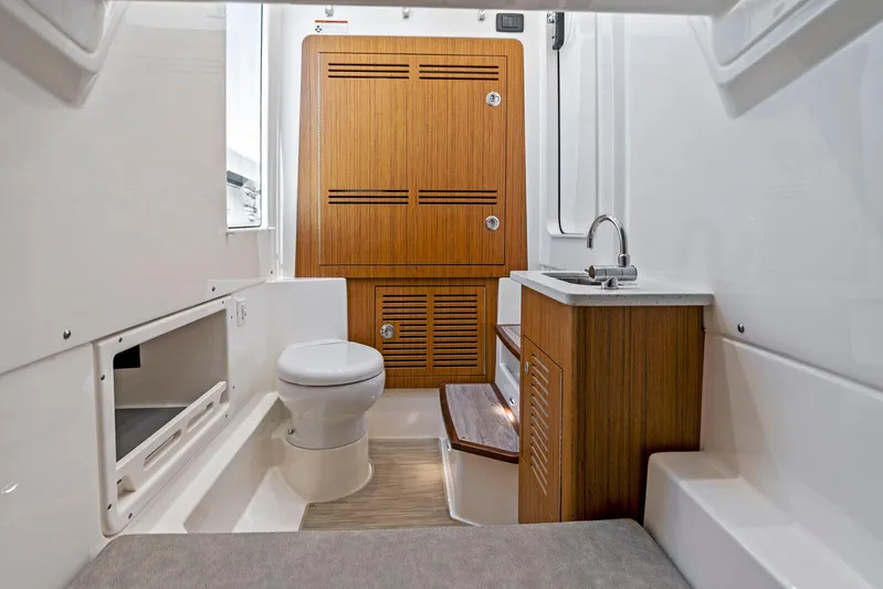  Yacht Photos Pics 2025 Solace 32 CS boat interior with wooden cabinetry, toilet, and sink.