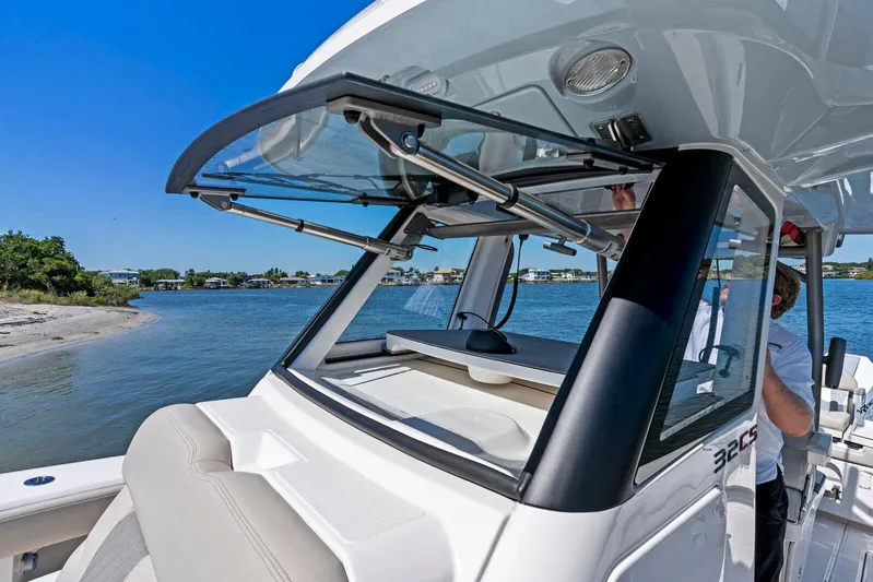  Yacht Photos Pics 2025 Solace 32 CS boat with open windshield, docked near a scenic shoreline.