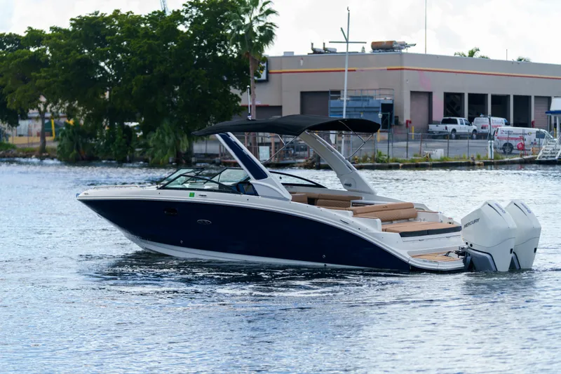  Yacht Photos Pics Sea Ray boat with dual Mercury engines cruising on a calm waterway near industrial buildings.