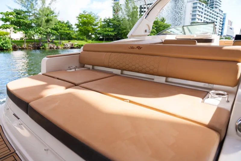  Yacht Photos Pics Luxurious Sea Ray boat with tan leather seating, docked near lush greenery.