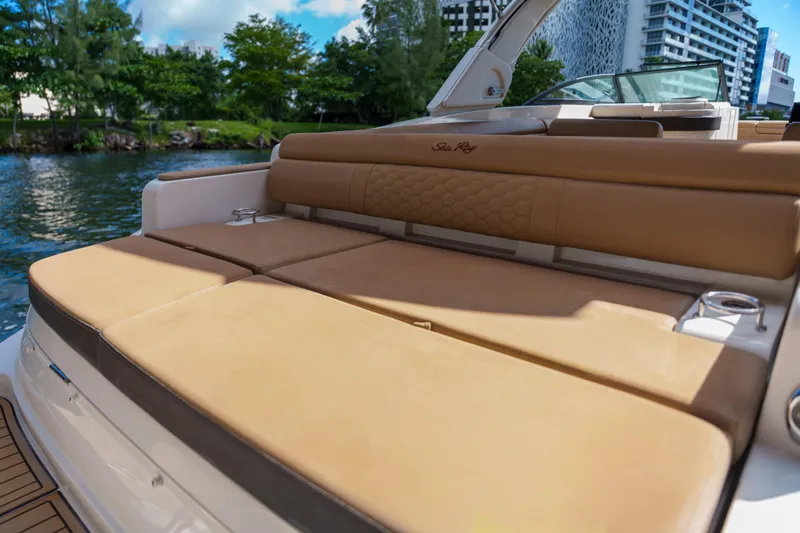  Yacht Photos Pics Luxurious Sea Ray boat seating with tan cushions, docked near lush greenery and modern buildings.