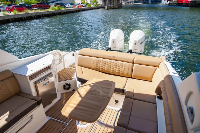  Yacht Photos Pics Luxury Sea Ray boat interior with tan seating, wooden table, and dual Mercury engines on a sunny day.