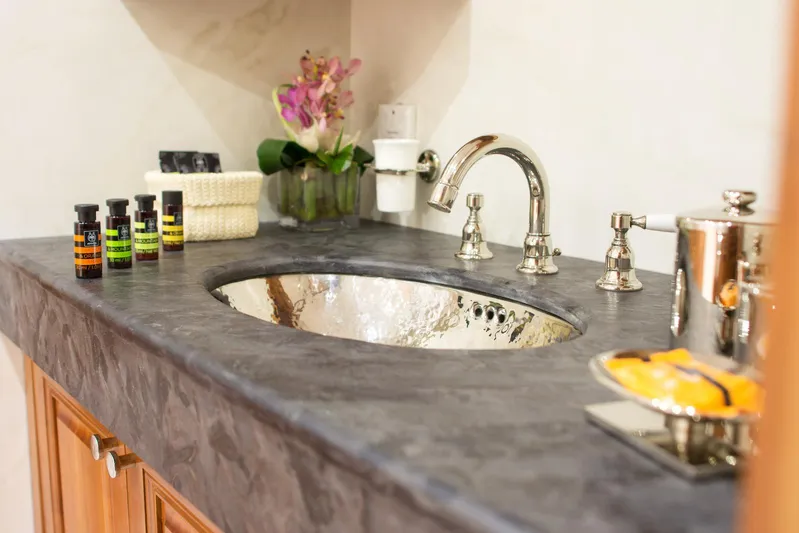 Parvati Yacht Photos Pics Luxurious bathroom sink with chrome faucet, toiletries, and decorative flowers on a marble countertop.