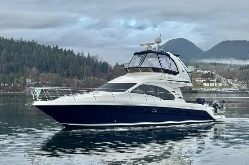 Covetime II Yacht Photos Pics 2006 Sea Ray 44 Sedan Bridge yacht on calm water, forested hills in background.