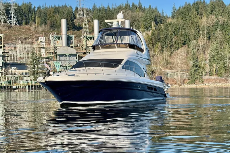 Covetime II Yacht Photos Pics 2006 Sea Ray 44 Sedan Bridge yacht on calm water, surrounded by industrial and forested landscape.