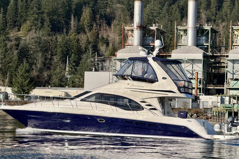 Covetime II Yacht Photos Pics 2006 Sea Ray 44 Sedan Bridge yacht cruising near industrial backdrop and forest.