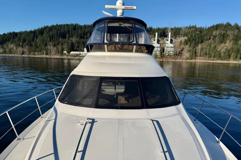 Covetime II Yacht Photos Pics 2006 Sea Ray 44 Sedan Bridge yacht on serene water with forested shoreline.