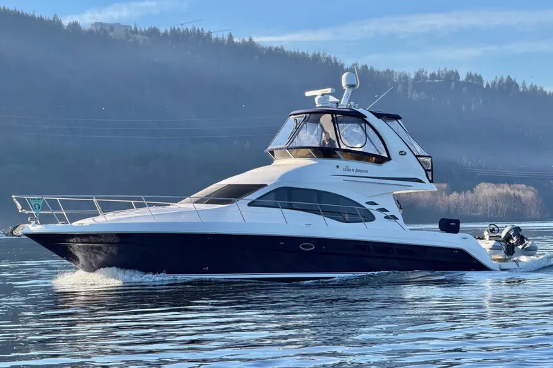 Covetime II Yacht Photos Pics 2006 Sea Ray 44 Sedan Bridge yacht cruising on a serene lake with forested hills.