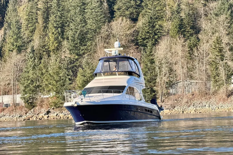 Covetime II Yacht Photos Pics 2006 Sea Ray 44 Sedan Bridge yacht on calm water, surrounded by forested shoreline.