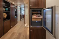 Modern yacht interior with open fridge, wooden flooring, and elegant shelving.