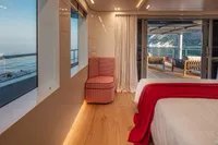 Luxurious yacht interior with ocean view, featuring modern decor and a cozy red chair.
