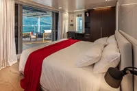 Luxurious bedroom on Custom K584 Hull 2 yacht, featuring a red throw and scenic view, 2024.