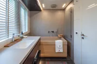 Modern bathroom with wooden tub, sleek sink, and blinds. Custom K584 Hull 2, 2024 model.
