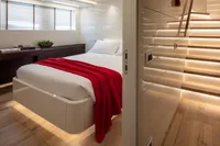Modern bedroom with red blanket, wooden floors, and ambient lighting on a 2024 Custom K584 Hull 2.