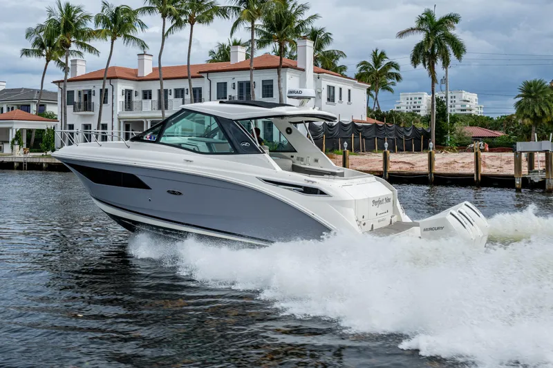  Yacht Photos Pics 2023 Sea Ray Sundancer 320 Outboard cruising near waterfront homes, surrounded by palm trees.