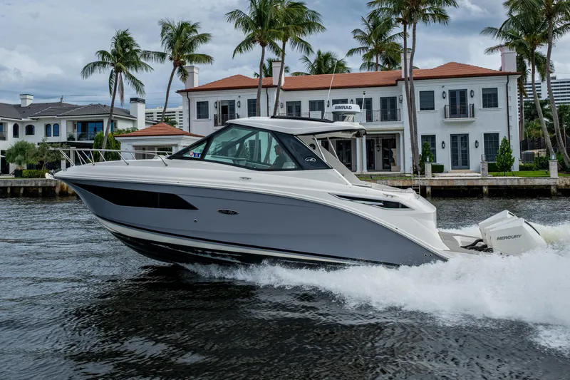  Yacht Photos Pics 2023 Sea Ray Sundancer 320 Outboard cruising near waterfront homes, surrounded by palm trees.