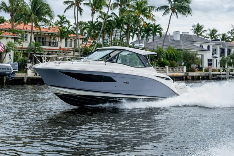  Yacht Photos Pics 2023 Sea Ray Sundancer 320 Outboard cruising on a scenic waterfront with palm trees.