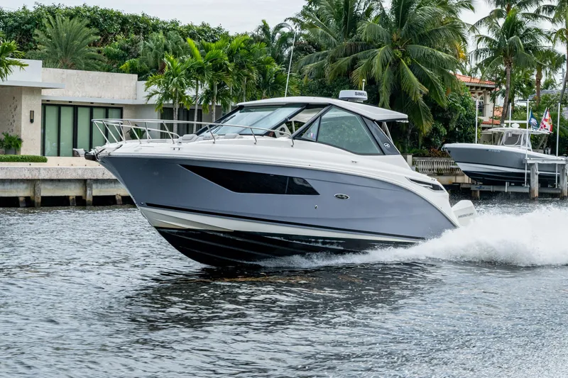  Yacht Photos Pics 2023 Sea Ray Sundancer 320 Outboard cruising on a scenic waterway with lush greenery.