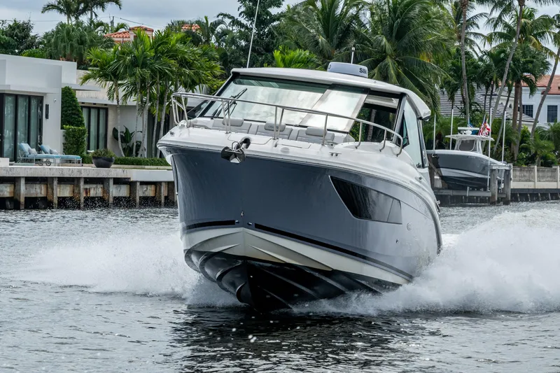  Yacht Photos Pics 2023 Sea Ray Sundancer 320 Outboard cruising on a scenic waterway with palm trees.