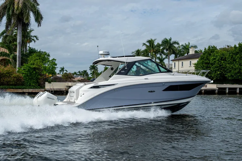  Yacht Photos Pics 2023 Sea Ray Sundancer 320 Outboard cruising on a scenic waterway with palm trees.