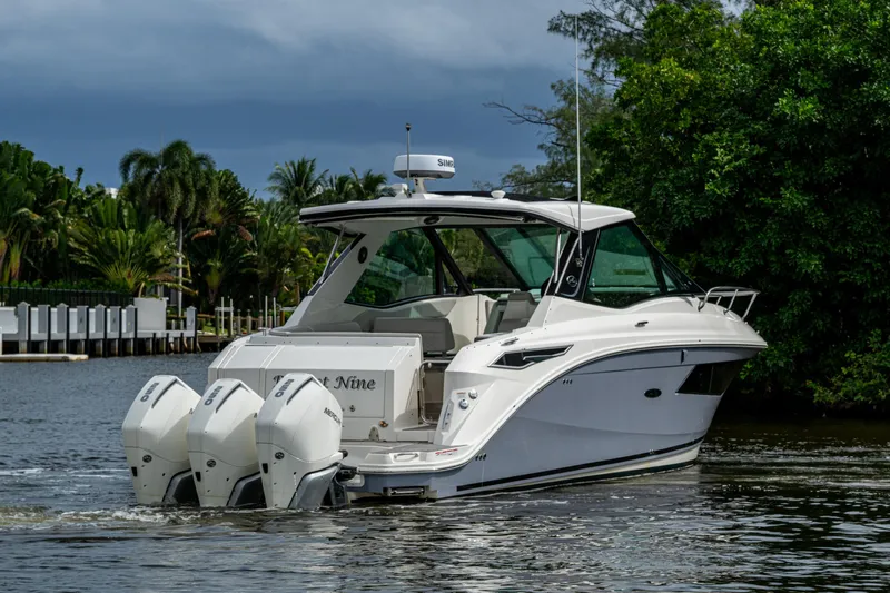  Yacht Photos Pics 2023 Sea Ray Sundancer 320 Outboard cruising on a scenic waterway with lush greenery.