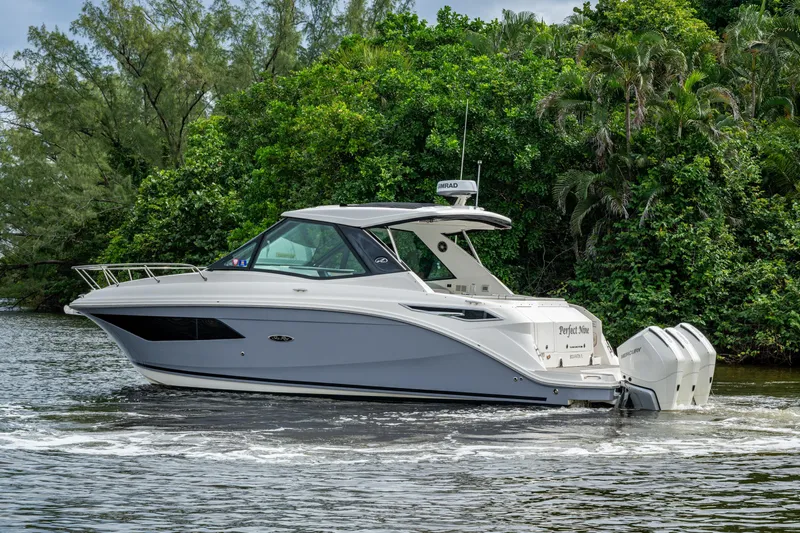 Yacht Photos Pics 2023 Sea Ray Sundancer 320 Outboard cruising on a scenic waterway with lush greenery.