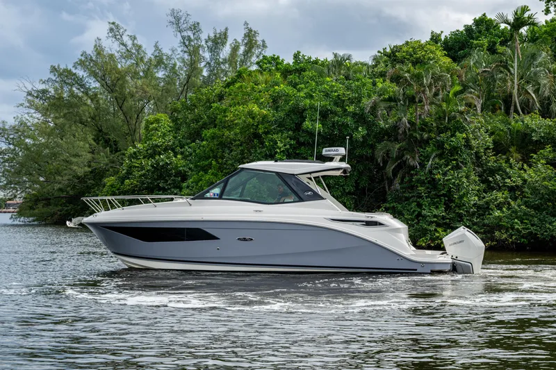  Yacht Photos Pics 2023 Sea Ray Sundancer 320 Outboard cruising on a serene waterway, surrounded by lush greenery.