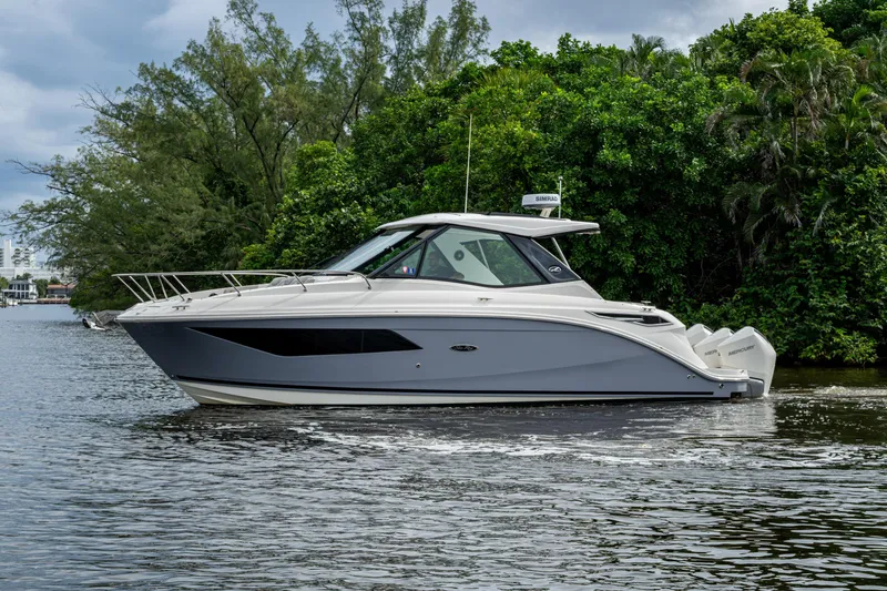  Yacht Photos Pics 2023 Sea Ray Sundancer 320 Outboard cruising on a serene waterway, surrounded by lush greenery.