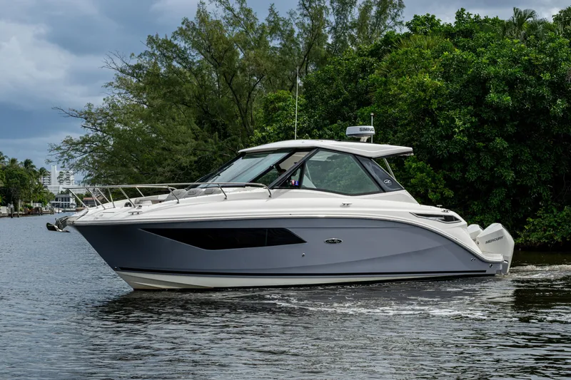  Yacht Photos Pics 2023 Sea Ray Sundancer 320 Outboard cruising on a serene waterway, surrounded by lush greenery.
