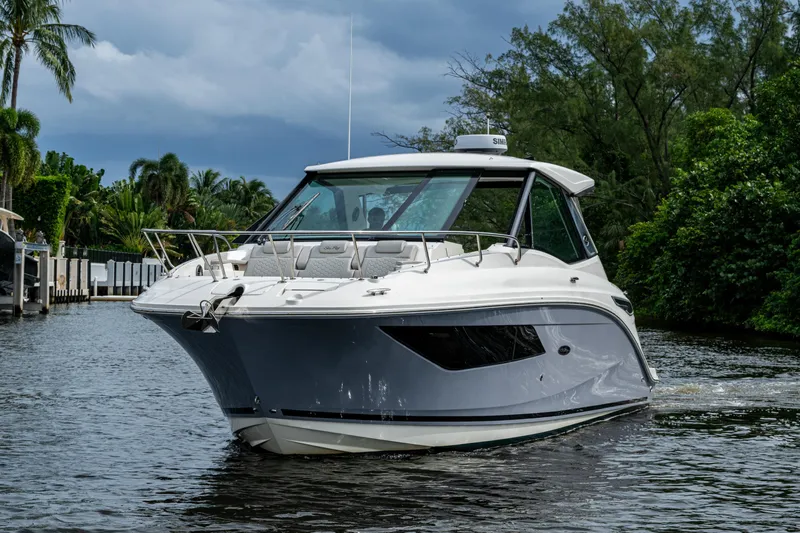  Yacht Photos Pics 2023 Sea Ray Sundancer 320 Outboard cruising on a scenic waterway with lush greenery.